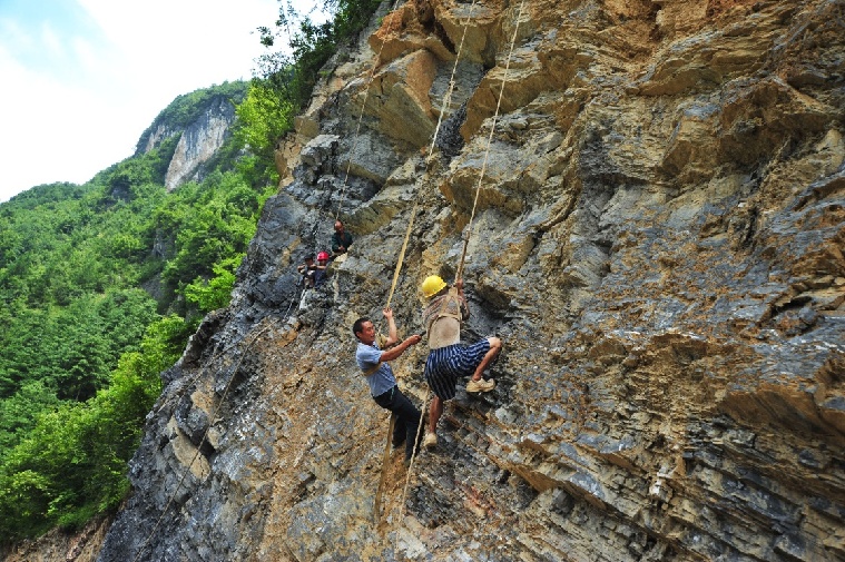 王光国(戴红色头盔者)和村民一起在悬崖上修路(2010年8月5日杨顺丕摄)