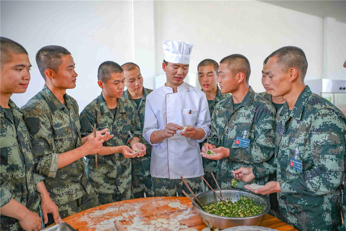 新兵们在向炊事员学习如何包饺子.