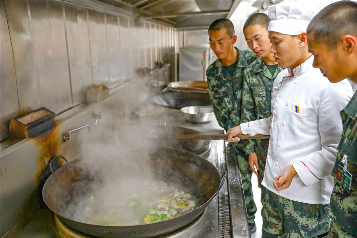 新兵们在向炊事员请教煮水饺秘诀.